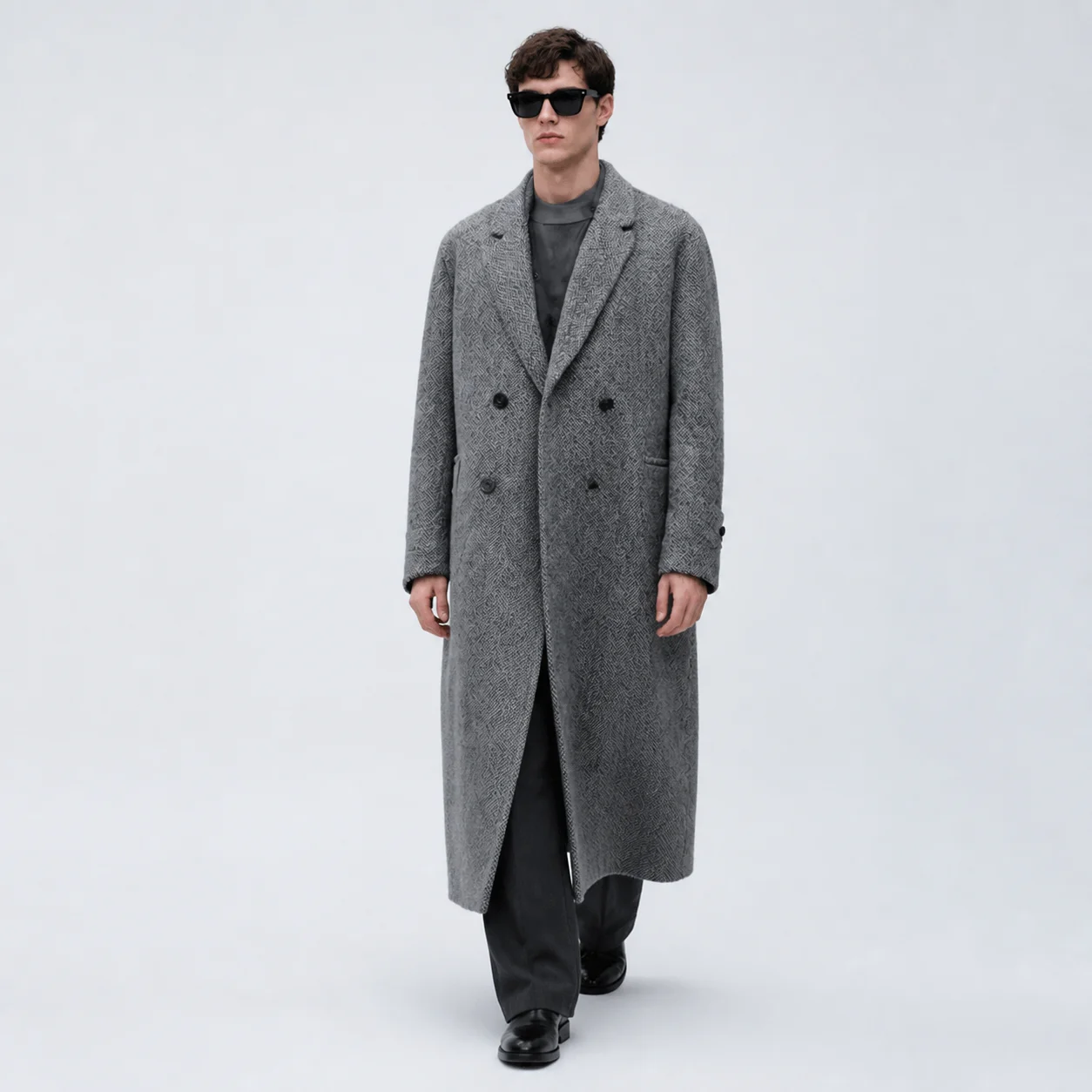 Character key frame — full-length figure in a grey overcoat, seamless backdrop